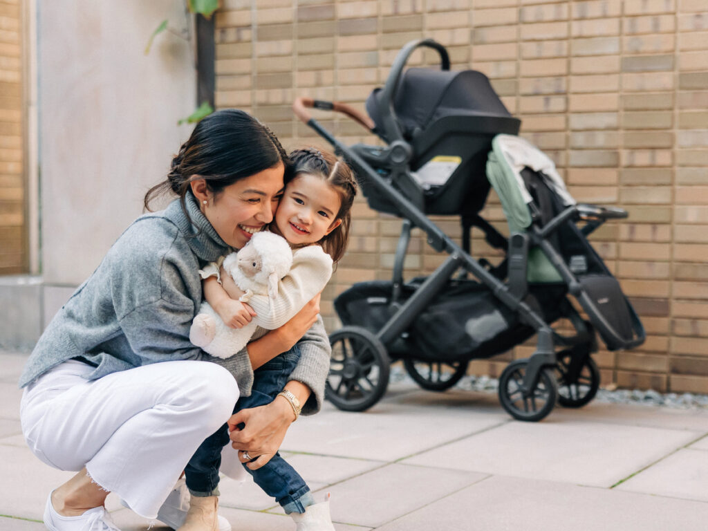A loving mom and her daughter disembark from a stroll in the Vista V2 stroller equipped with a RumbleSeat and Mesa Max infant car seat