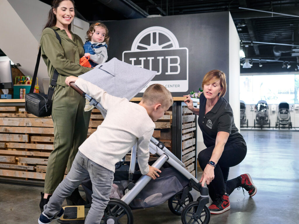 UPPAbaby customer service specialist advising a parent on stroller features at the UPPAbaby Hub, highlighting personalized customer support and product expertise.